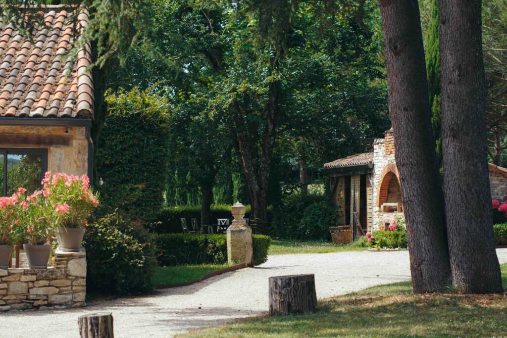 Allée arborée et bâtiments en pierre du Domaine de Labarthe dans le Lot